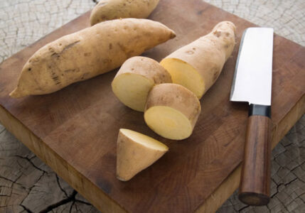 Japanese yams on a cutting board with a knife.